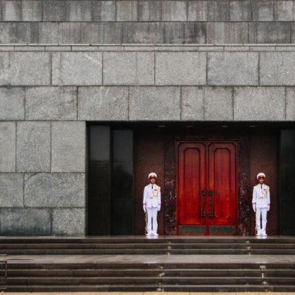Guards dressed in white, standing at the top of the stairs outside the Ho Chi Minh Mausoleum in Vietnam.
